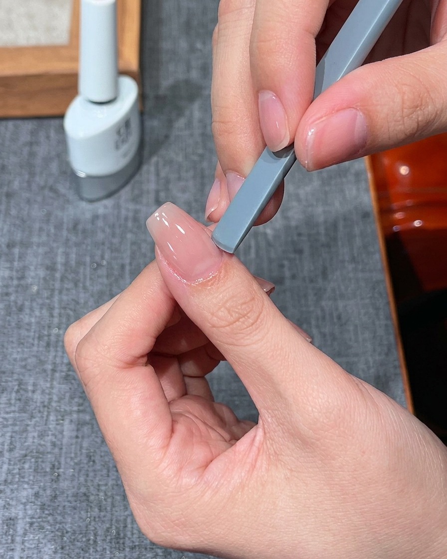 Ein Finger unter einer kleinen UV-LED-Minilampe zum Aushärten.