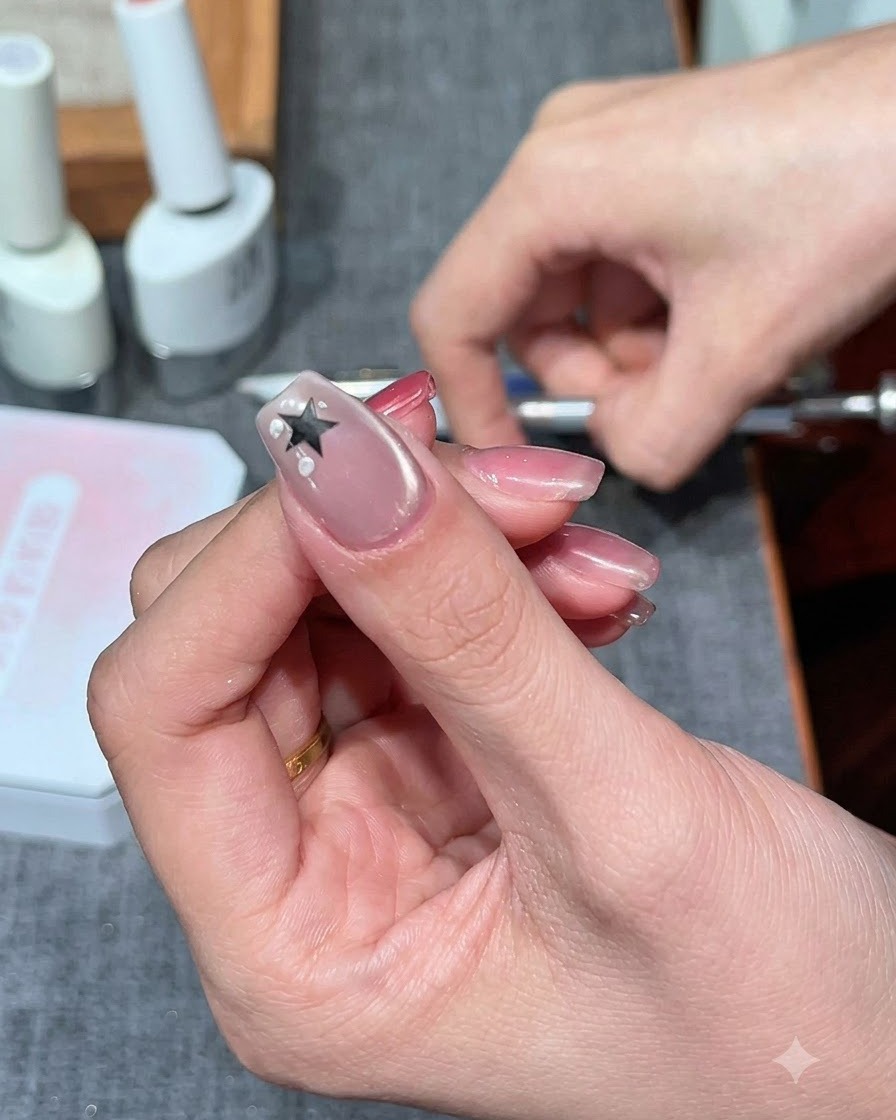 Ein fusselfreier Schwammstempel tupft milchweißes Gel um einen Sternaufkleber auf einem Fingernagel.