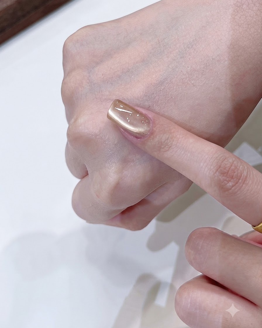 Ein Magnetwerkzeug formt eine weiche, einseitige Lichtreflexion auf einem Champagner-Gold Cat-Eye-Nagel.