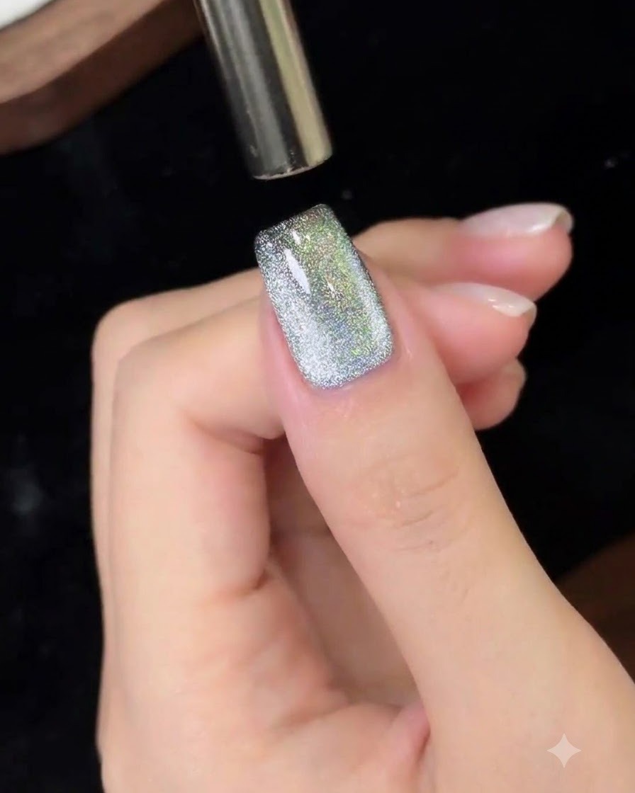 Ein magnetisches Werkzeug wird von oben nach unten über einen Cat-Eye-Gel-Nagel bewegt.