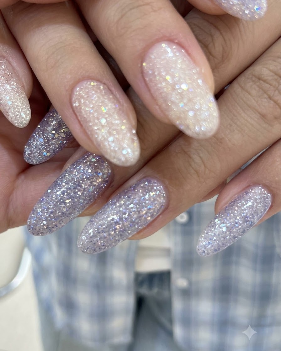 Eine Nahaufnahme von Händen mit ineinander verschränkten Fingern, die glänzende rosafarbene Nude- und lila Glitzer-Gel-Nägel zeigen.