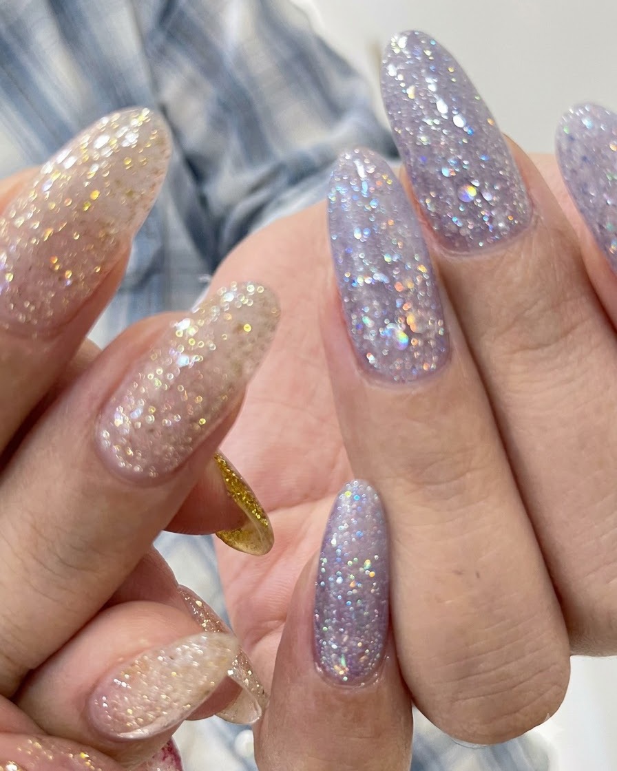 Eine Nahaufnahme von lila Glitter-Strukturnägeln mit einer sauberen Nagelhautlinie.