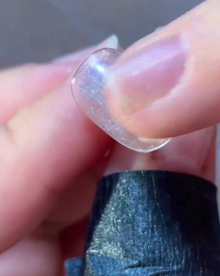 Ein feiner Liner-Pinsel trägt pinke Geltails um ein Sternendesign auf einem Nagel auf.