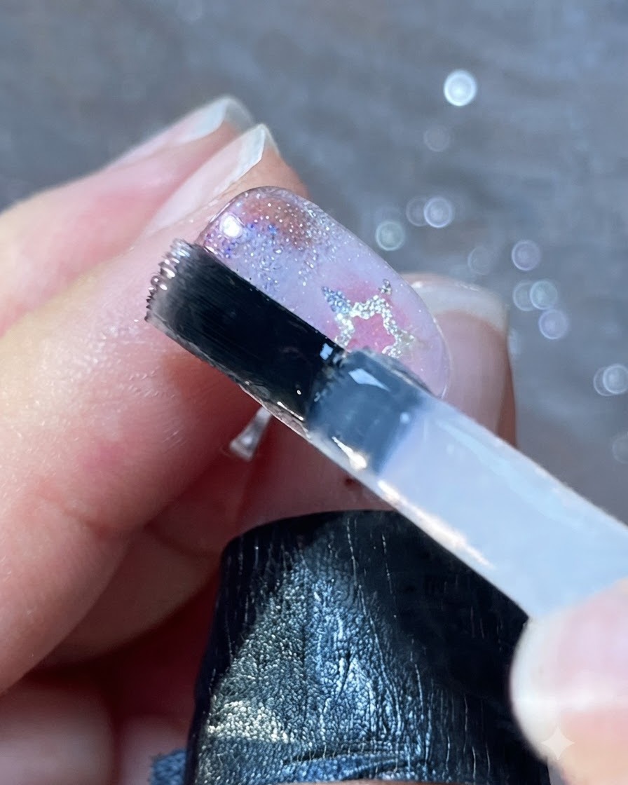 Ein Nagelpinsel trägt eine glatte Schicht klaren Top Coats über verzierte Nägel auf.