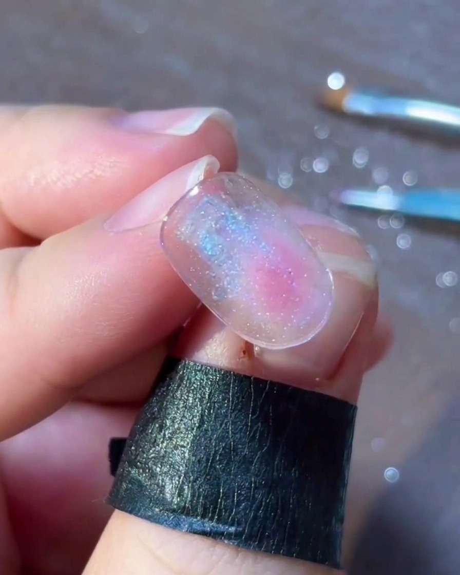 Eine detaillierte Ansicht kleiner bunter Punkte und Flocken, die zart um ein silbernes Stern-Nailart-Design angeordnet sind.