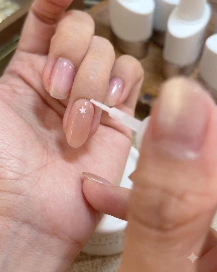 Ein Werkzeug, das einen kleinen holografischen Sternaufkleber auf die glänzende Base-Gel-Oberfläche eines Fingers platziert.