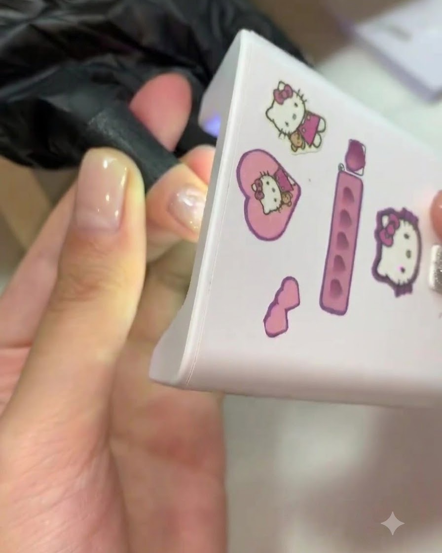 Ein Finger wird zum Aushärten in eine rosa Mini-UV/LED-Lampe gesteckt.