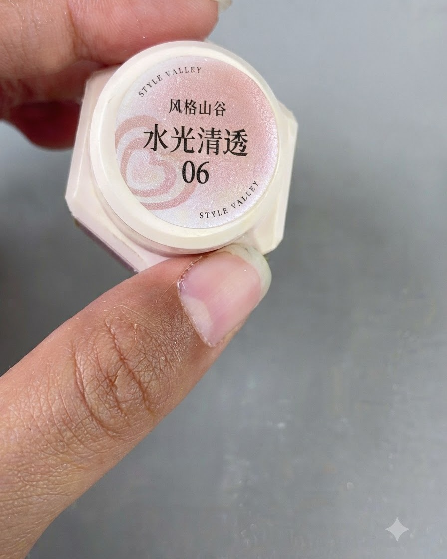 Eine Nahaufnahme einer Hand, die ein kleines Glas mit pinkem translucenten Cat-Eye-Gel der Nummer 06 hält.