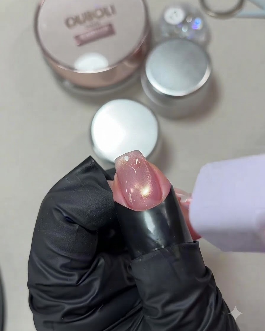 Ein Fingernagel mit einem leuchtenden Cat-Eye-Gel-Design wird unter einer kleinen, handgeführten violetten UV/LED-Lampe ausgehärtet.
