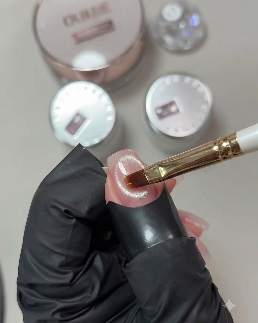 Ein Gelpinsel trägt eine klare Schicht Verstärkungsgel auf eine fertige Cat-Eye-Nageloberfläche auf.