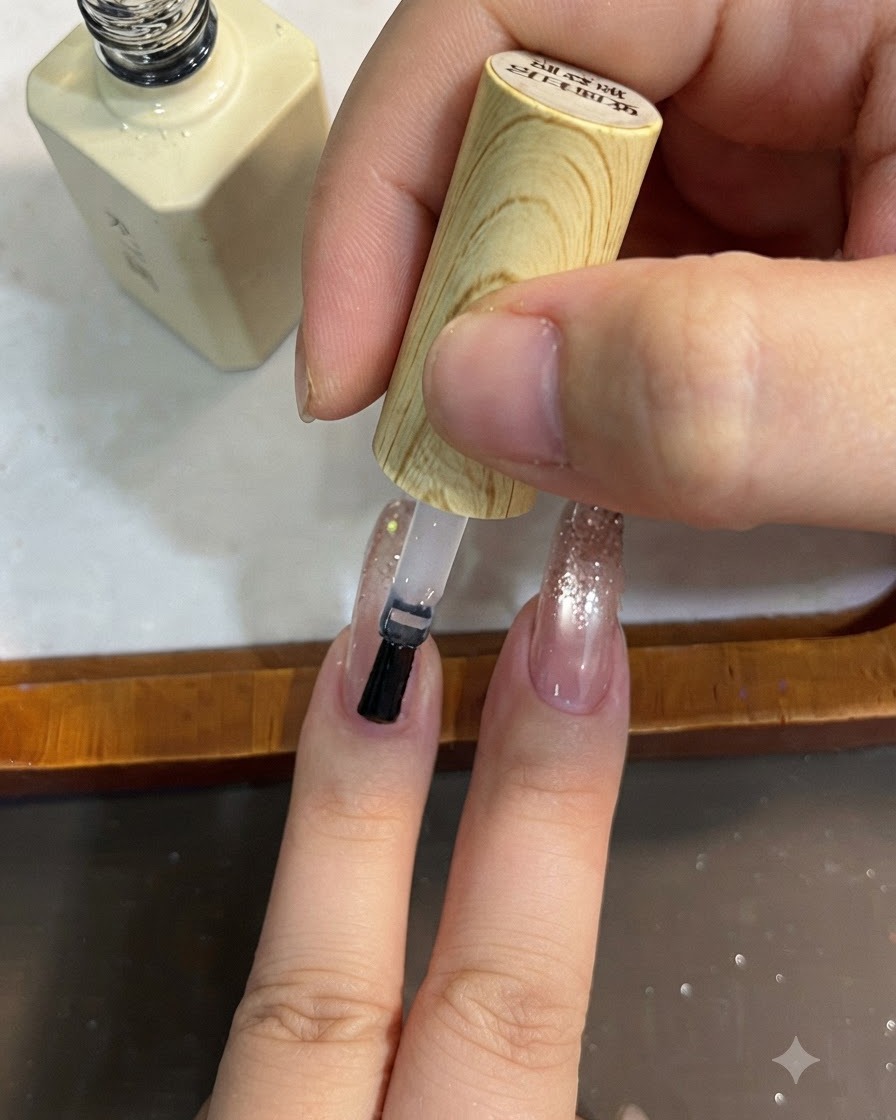 Ein Pinsel trägt klaren Topcoat über ein Glitter-Verlaufs-Nageldesign auf.