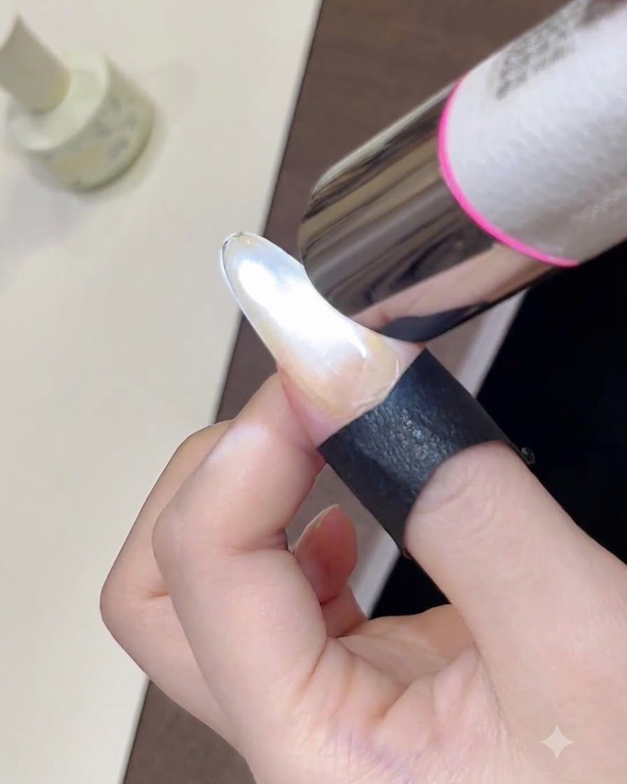 Eine Nahaufnahme einer tragbaren Mini-UV-Lampe, die einen frisch gestylten, schimmernden Cat-Eye-Gellack auf einem Fingernagel aushärtet.