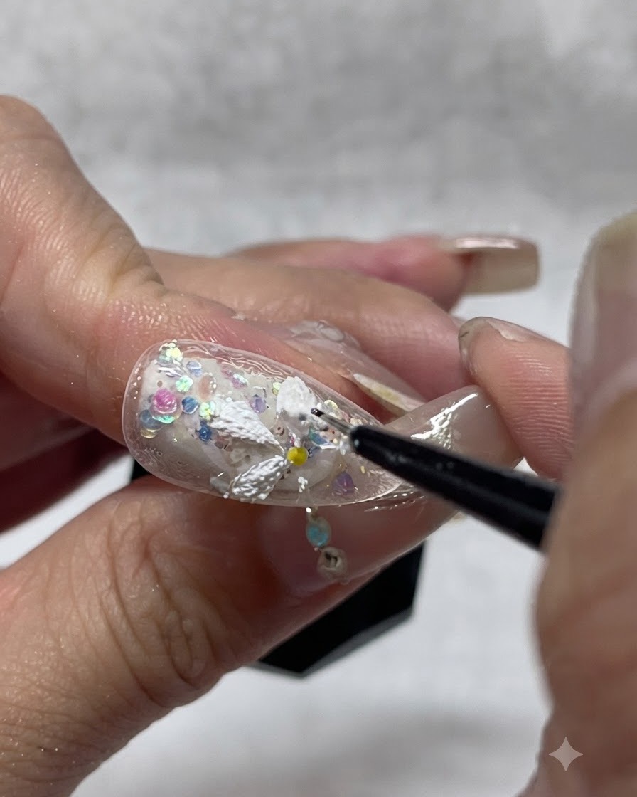 Eine Nageldesignerin fügt zusätzliches weißes Struktur-Gel auf gemalte Gänseblümchen-Blütenblätter auf, um die 3D-Tiefe und Deckkraft zu verstärken.