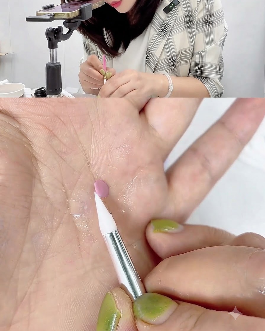 Ein weißer Silikon-Carving-Pen berührt und rollt den Rand einer kleinen rosa Gelscheibe auf einer Handfläche.