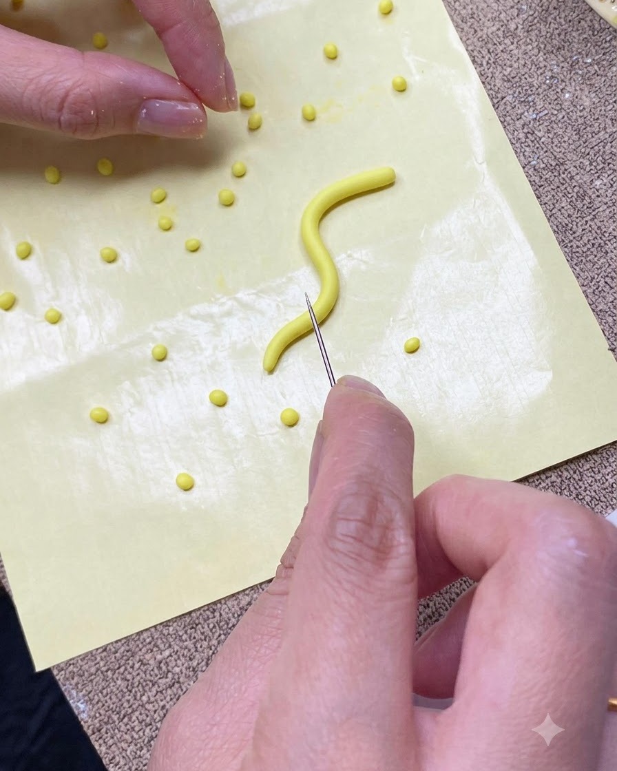 Eine Nahaufnahme von Händen, die mit einem Nadelwerkzeug einen gelben Gelstreifen auf einer gelben Silikonmatte in kleine Portionen schneiden.