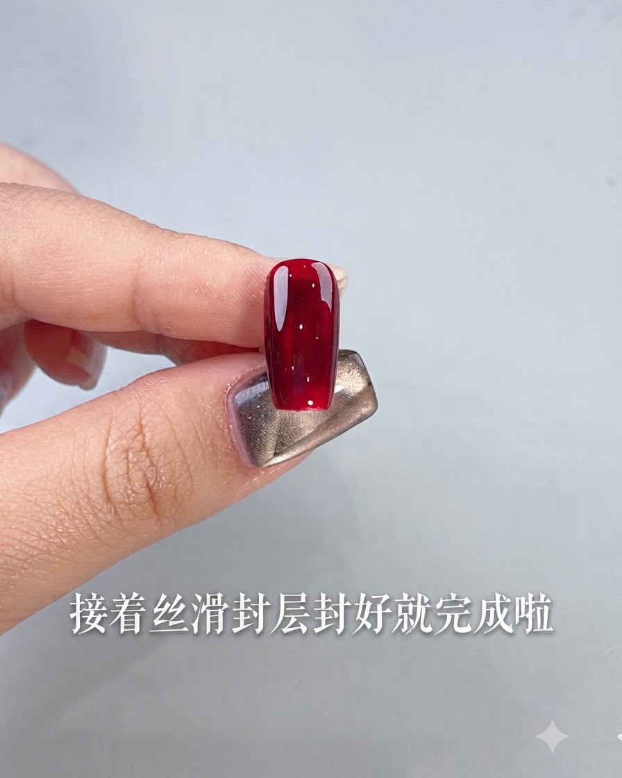 Ein einzelner Nagel, der mit glänzendem, ochsenblutrotem Gel-Polish vollendet ist, gehalten von einem Finger vor hellem Hintergrund.