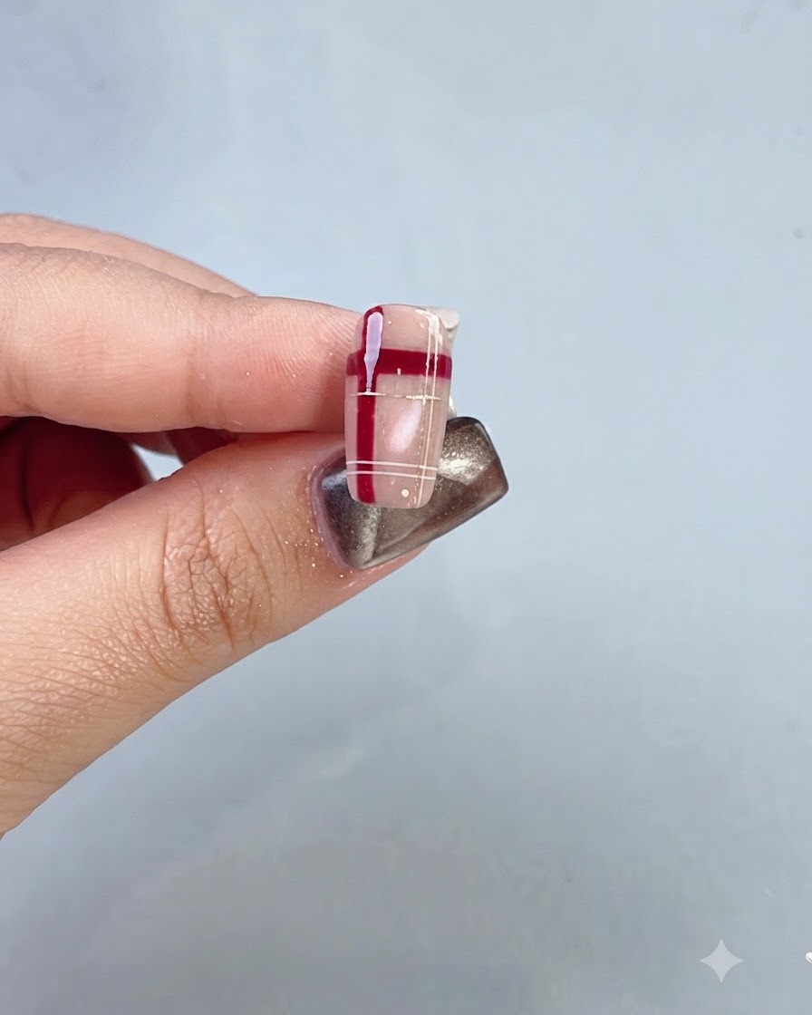 Eine Nahaufnahme eines vollendeten Nagels mit rotem Kristallgitter- und Karomuster.