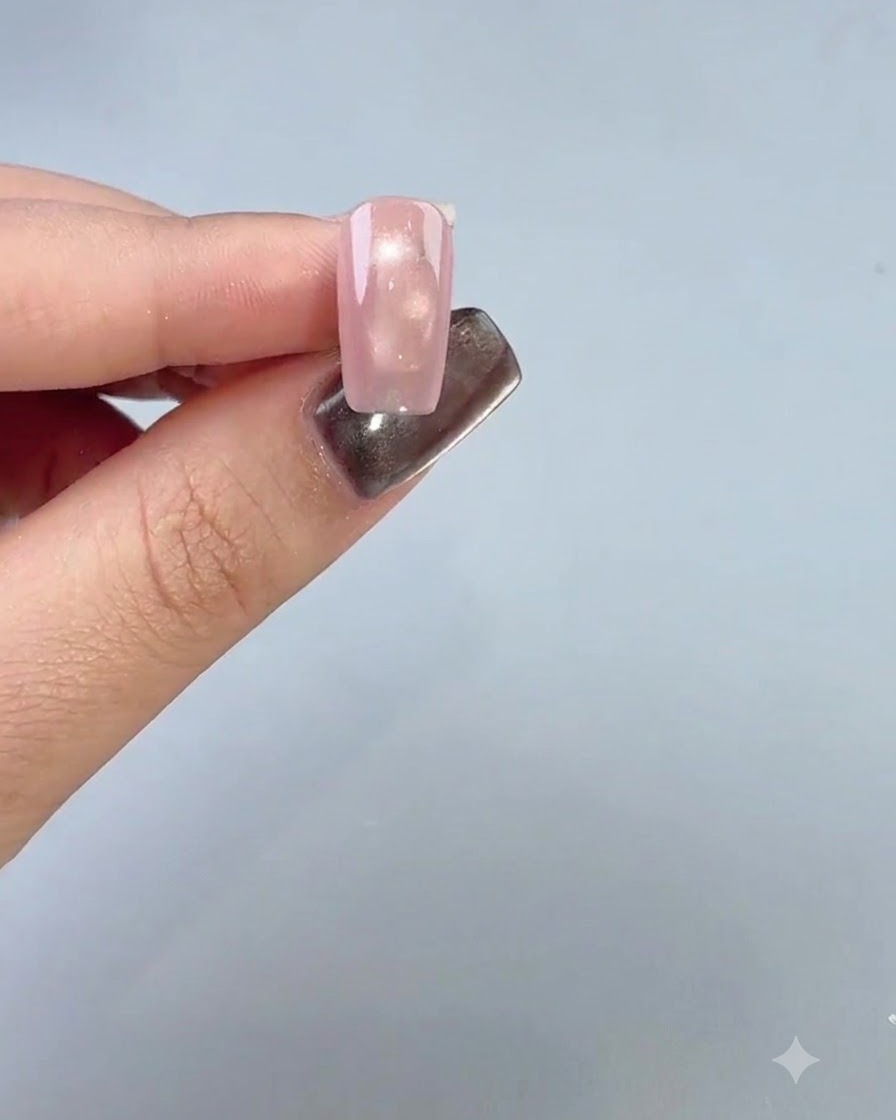 Ein manikürter Finger zeigt einen glatten Basislack, der auf den vierten Nagel aufgetragen wurde.
