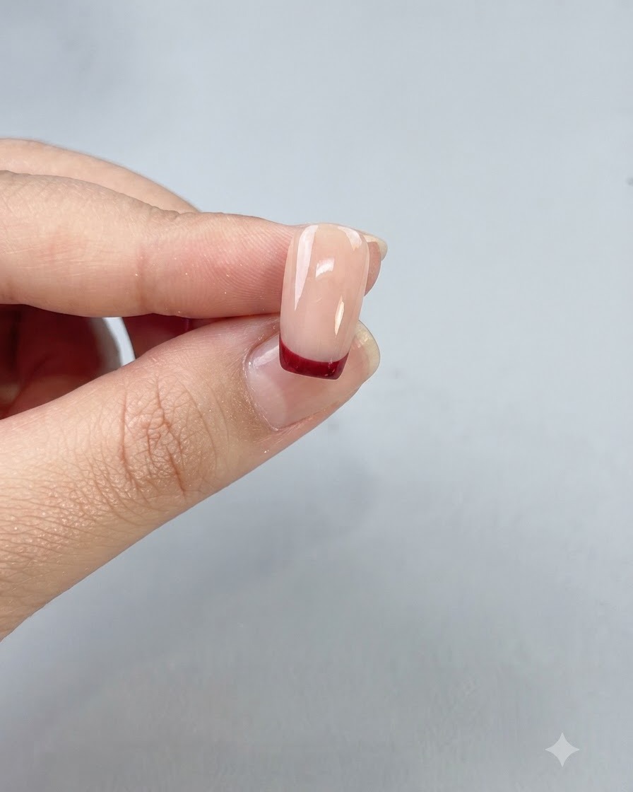 Ein fertiger Nagel mit einem sauberen ochsenblutroten French Tip, versiegelt unter einem glänzenden Top Coat.