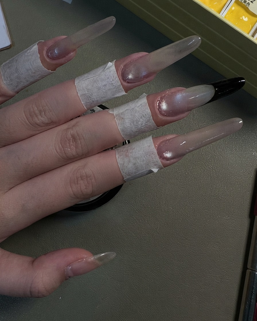 Eine Hand zeigt vier lange Stiletto-Nägel mit einem perlmuttfarbenen grauen Cat-Eye-Shimmer-Look.
