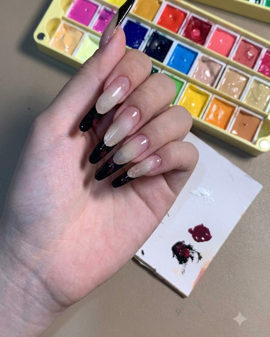 Eine Hand zeigt Stiletto-Nägel mit schwarzen French Tips und dunkelvioletten Rosen-Konturen.