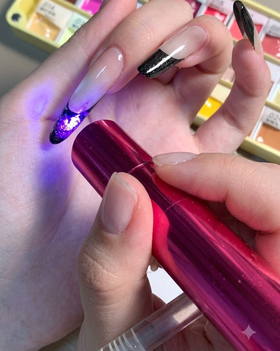 Eine Mini-UV-/LED-Lampe wird über einen Nagel gehalten, um die dunklen Zentrumsdetails eines floralen Designs auszuhärten.