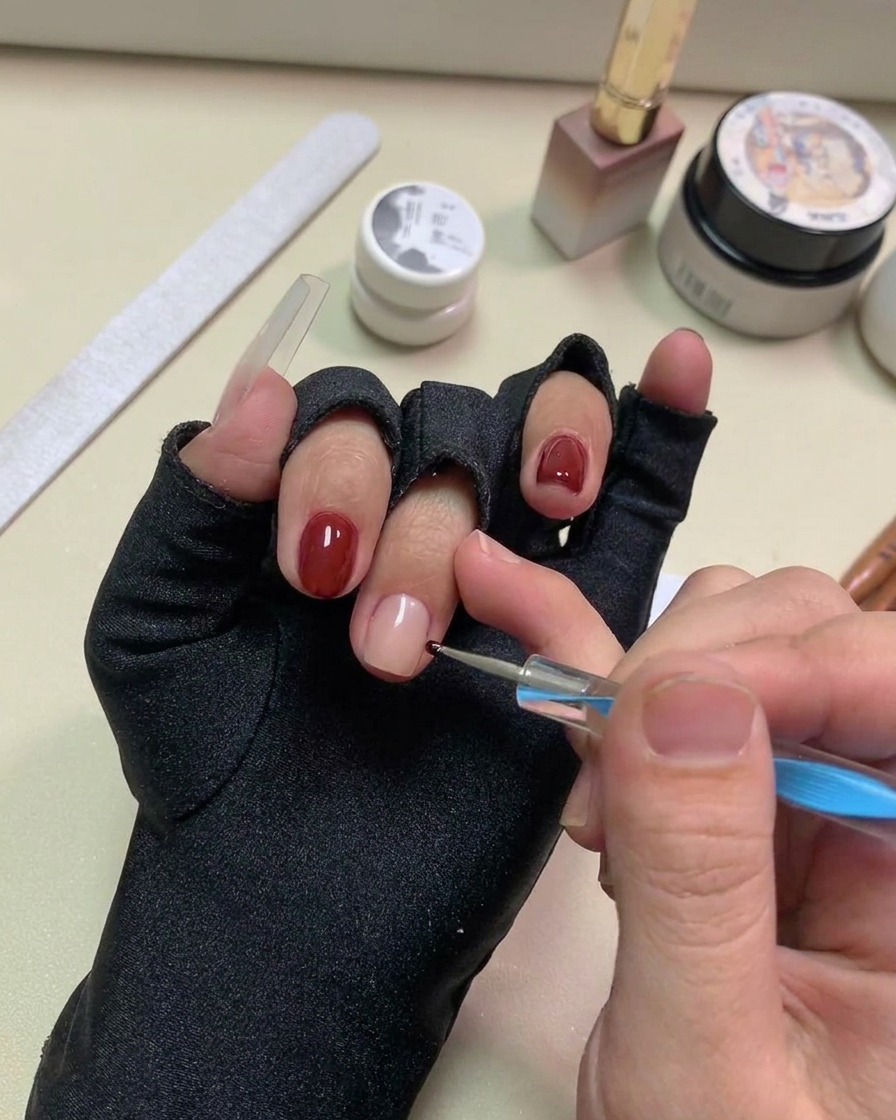Ein Dotting Tool setzt kleine, schwarze Gel-Punkte auf die nudefarbene Nageloberfläche.