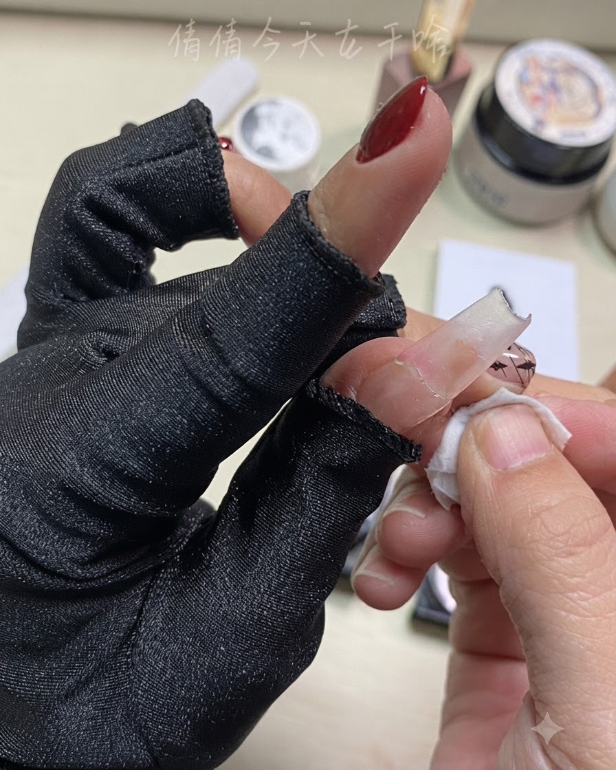 Nahaufnahme einer Hand, die einen Finger mit einem Reinigungspad in der Nähe der vorbereiteten Nail Art abwischt.