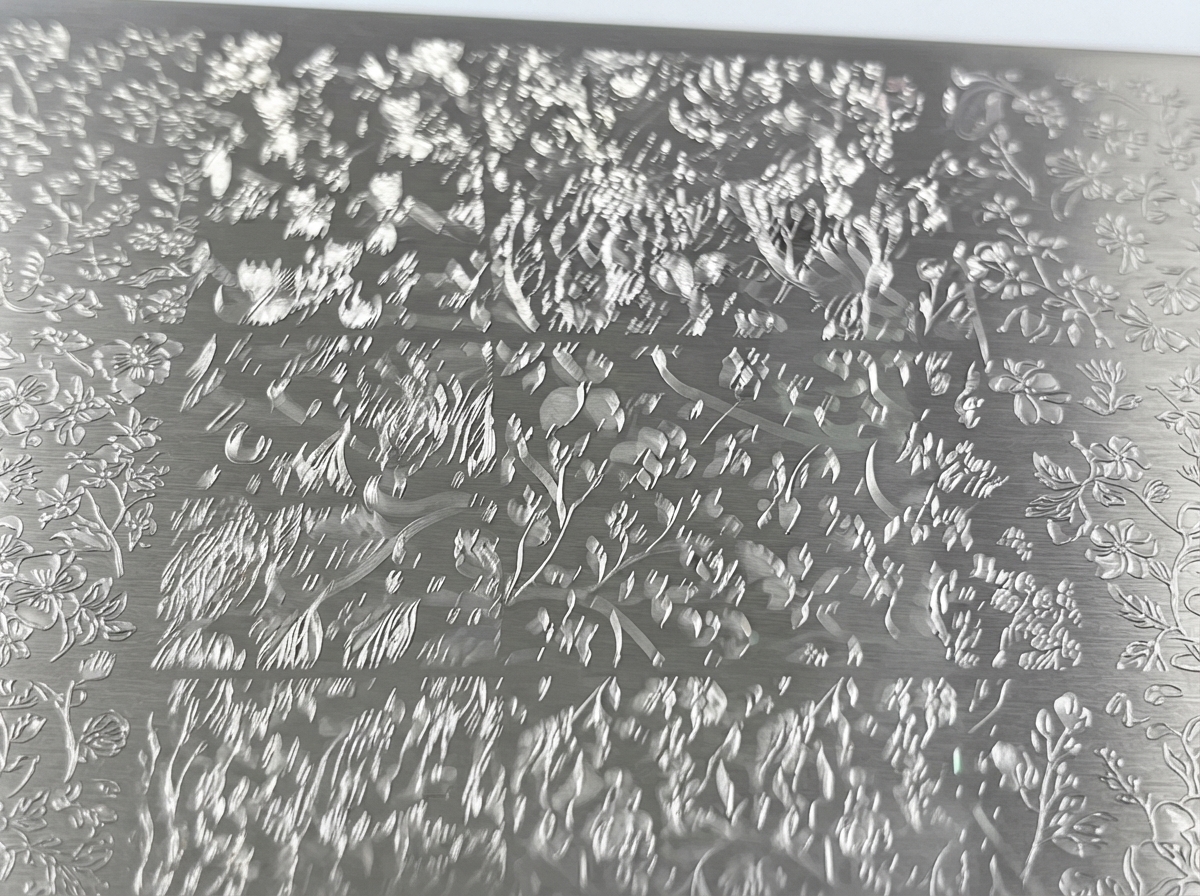 Nahaufnahme einer Metall-Stamping-Platte mit eingravierten detaillierten Blumendesigns.