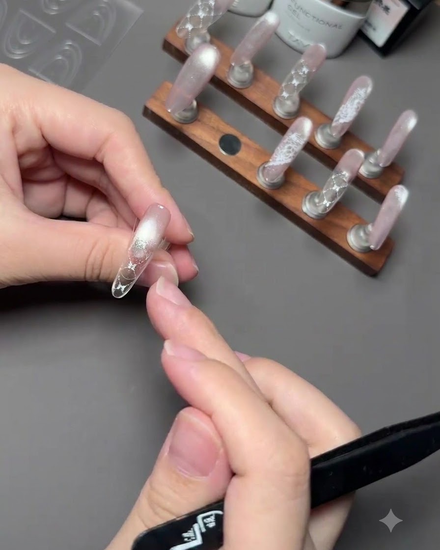 Eine Hand hält einen Pinsel, um pinkes Farbgel auf die Spitze eines Nagels über einem Führungsaufkleber aufzutragen.
