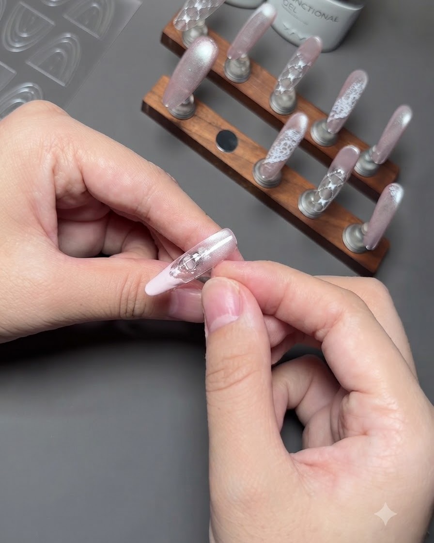 Nahaufnahme von Fingern, die sanft einen Führungsaufkleber von einem Nagel entfernen, um eine saubere pinke French-Spitze freizulegen.