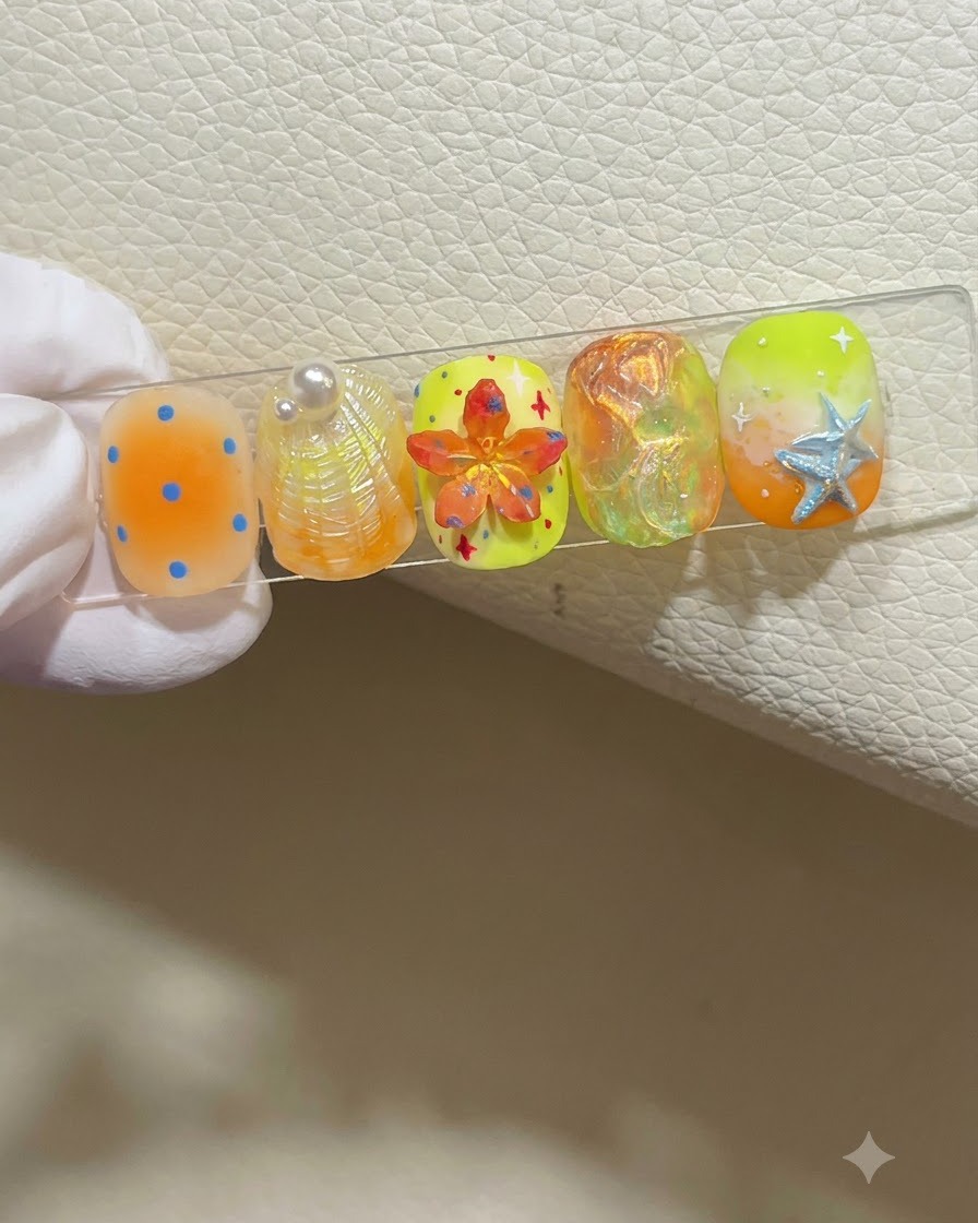 Eine behandschuhte Hand hält einen Nagel-Display-Ständer mit fünf bunten, sommerlichen Nail-Art-Designs.
