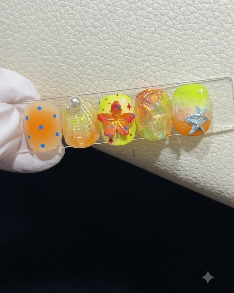 Nahaufnahme eines Nagel-Displays mit fünf sommerlichen Press-On-Nails mit 3D-Texturen.