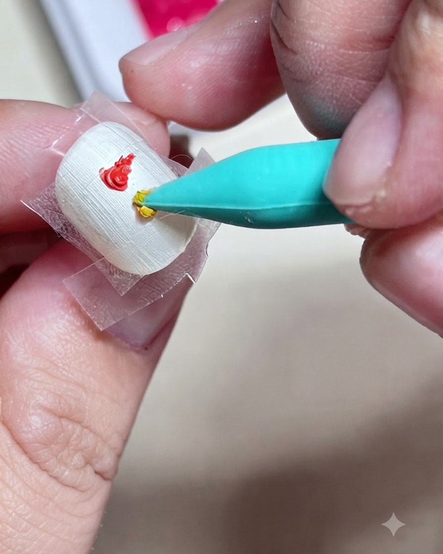 Ein Silikon-Tool setzt einen Tropfen gelbes Farbgel direkt unter einen roten Tupfer innerhalb des abgeklebten Quadrats auf einem Nagel.