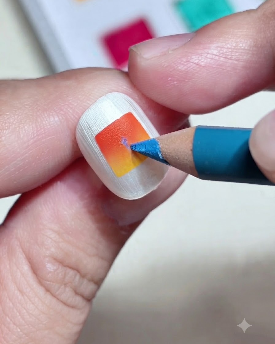Nahaufnahme eines blauen Buntstifts, der eine feine vertikale Linie auf einen orange-gelben Farbverlaufsnagel zeichnet.
