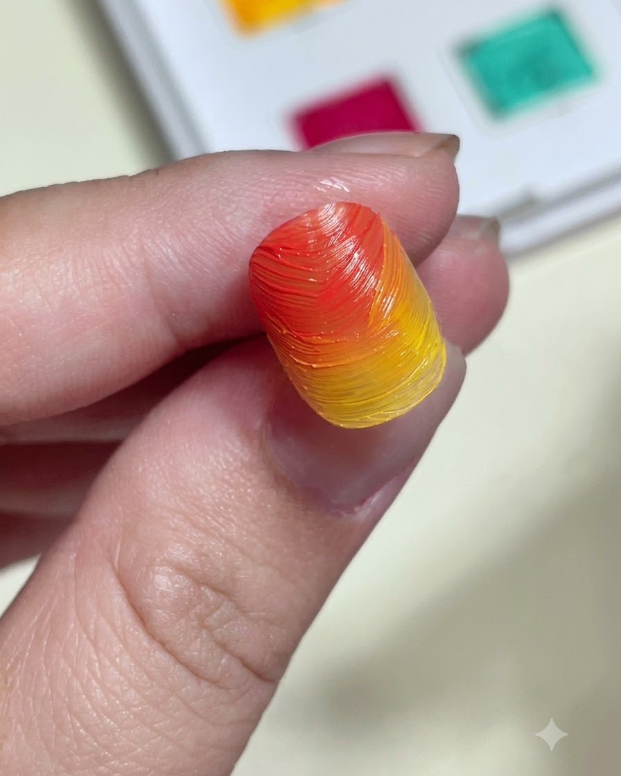 Ein Schwamm-Applikator reibt schimmerndes Aurora-Puder auf einen strukturierten, orange-gelben Farbverlaufsnagel.