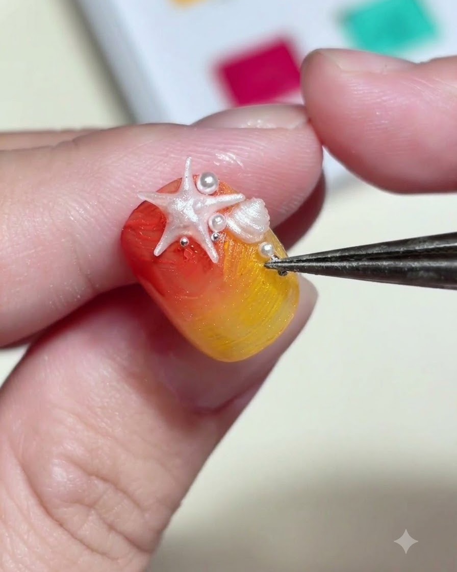 Eine Pinzette platziert winzige weiße Perlen und metallische Nieten um einen 3D-Seestern-Charm auf einem Nagel.