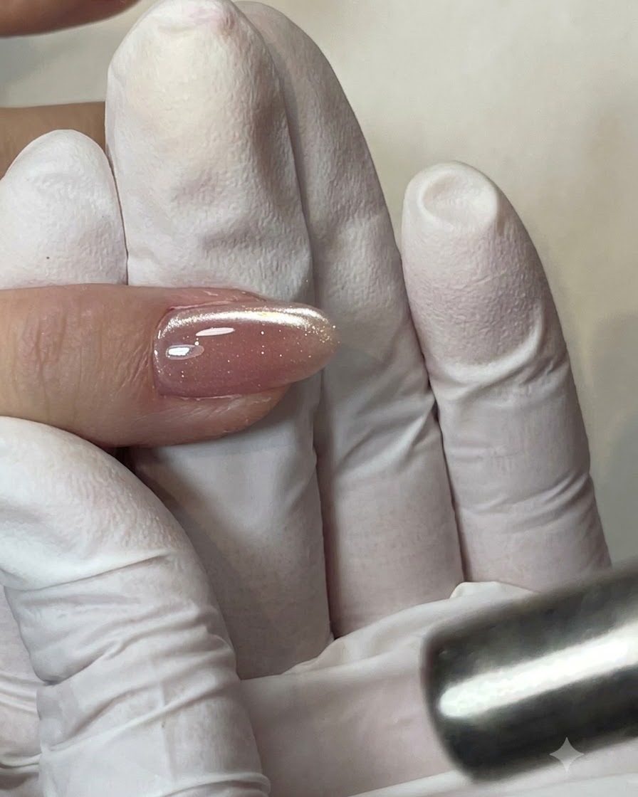 Ein flacher Gelpinsel trägt eine klare Schicht Base Coat auf die Nagelplatte auf.
