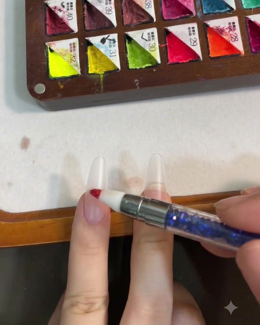Ein Silikontool tupft rosa Gel auf die Mitte eines Nagels, um einen Blush-Effekt zu erzeugen.
