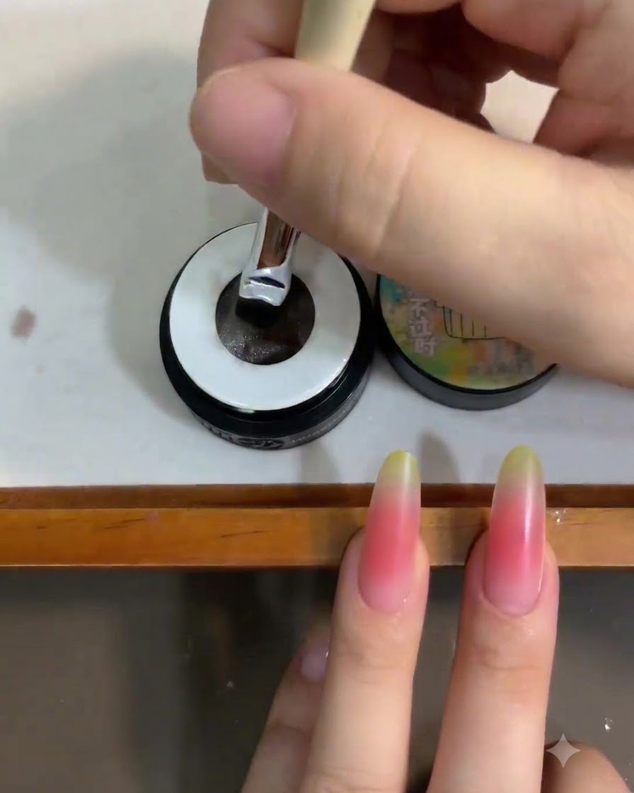 Ein Nagelpinsel wird in ein kleines Glas durchscheinendes, weißes Cat-Eye-Gel-Polish getaucht.
