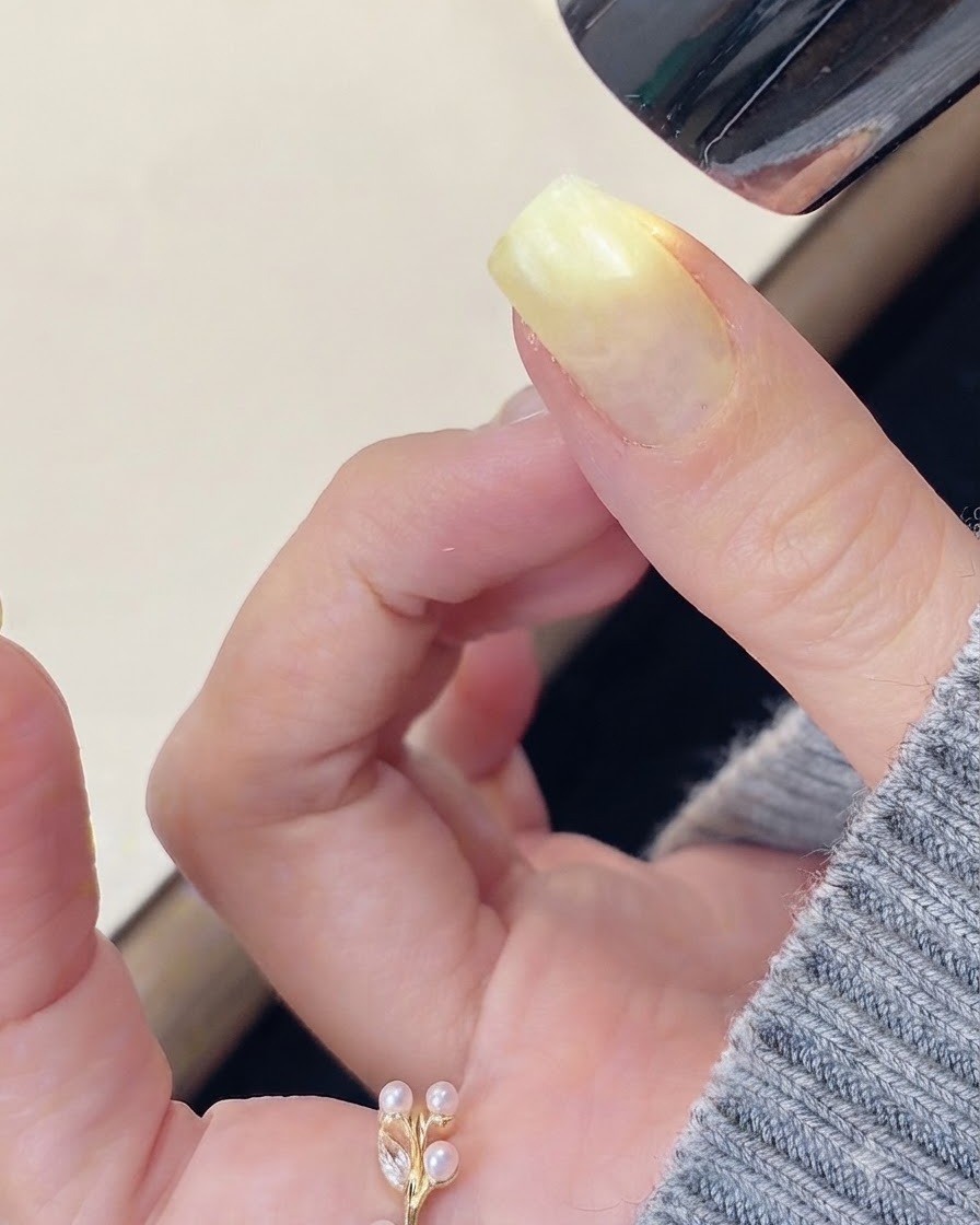 Ein Pinsel trägt klares, verstärkendes Aufbaugel auf die Oberfläche eines vorbereiteten Fingernagels auf.