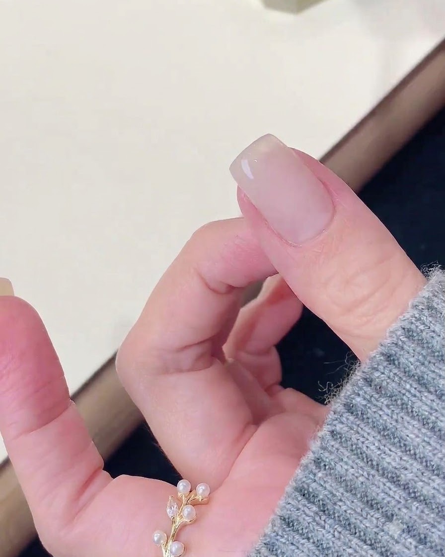 Ein Finger ruht nach dem Aushärten unter einer Nagellampe, während ein Tuch die Oberfläche reinigt.