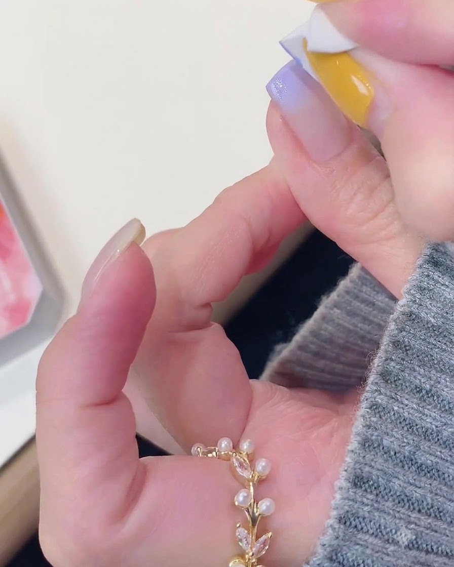 Ein Schwammwerkzeug tupft lila Gel sanft auf die Spitze eines manikürten Nagels.
