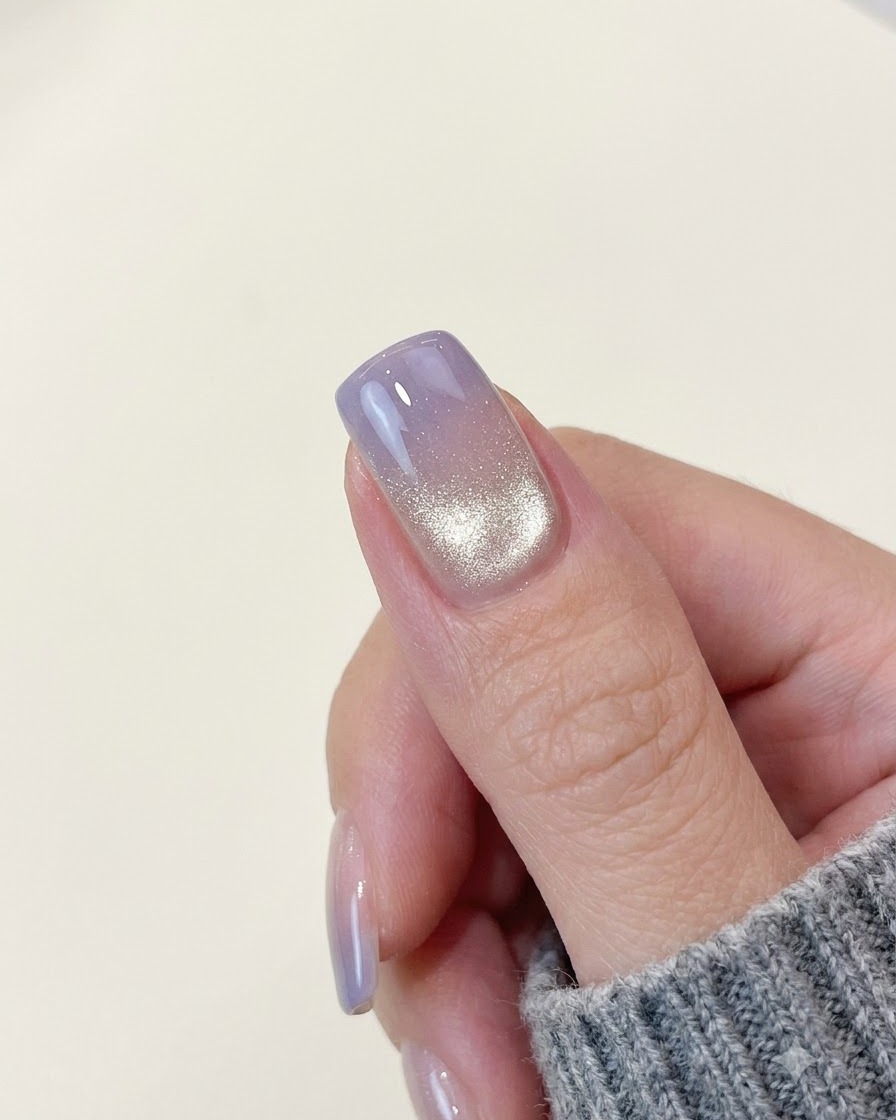 Ein fertiger lila Farbverlauf-Cat-Eye-Nagel zeigt ein helles, schimmerndes Lichtband in der Nähe der hinteren Kante.