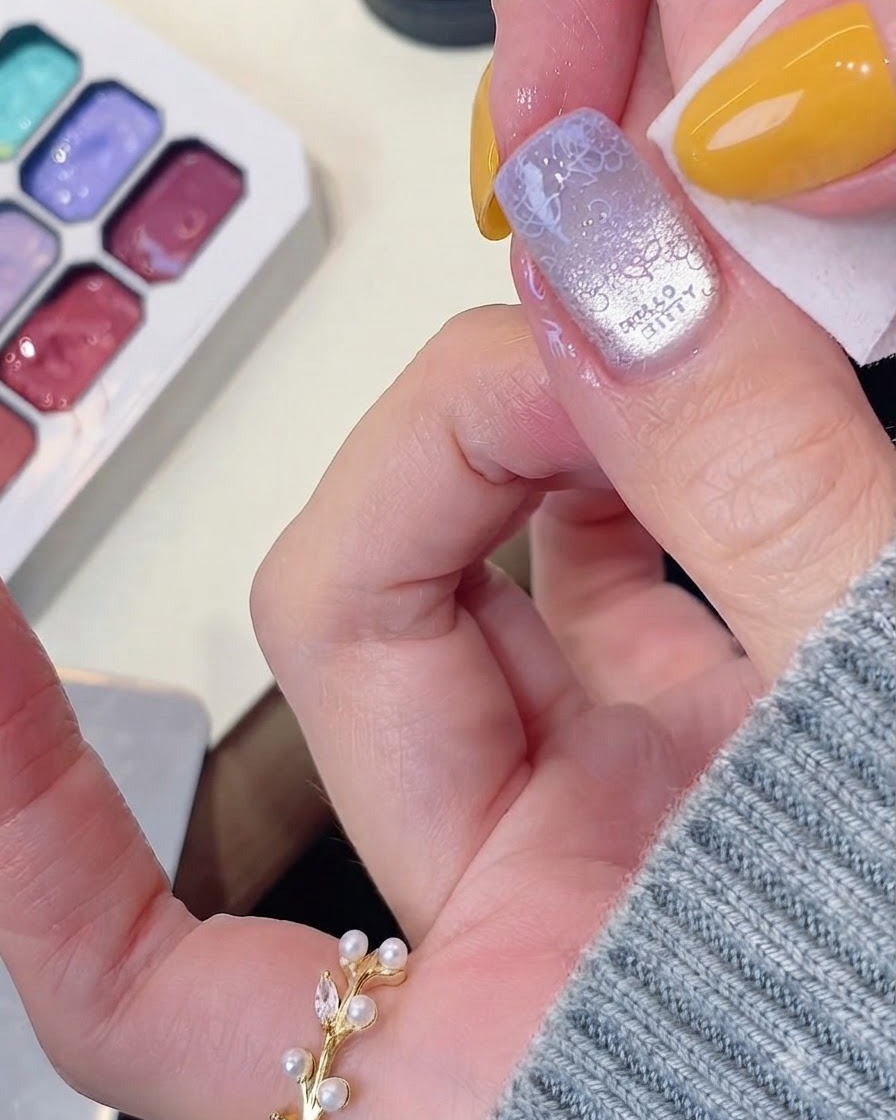 Ein Tuch reinigt überschüssiges Gel um die Kanten eines manikürten Nagels herum.