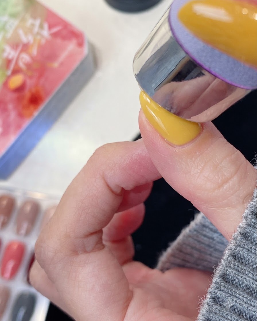 Ein manikürter Finger positioniert unter einer UV- oder LED-Nagellampe zum Aushärten.
