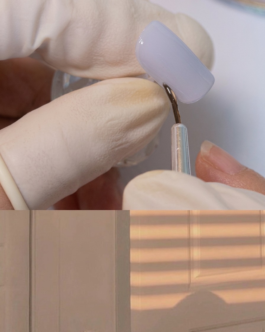Ein feiner Liner-Pinsel, der dickes Klebegel um den Rand eines matten grauen Nagels aufträgt.