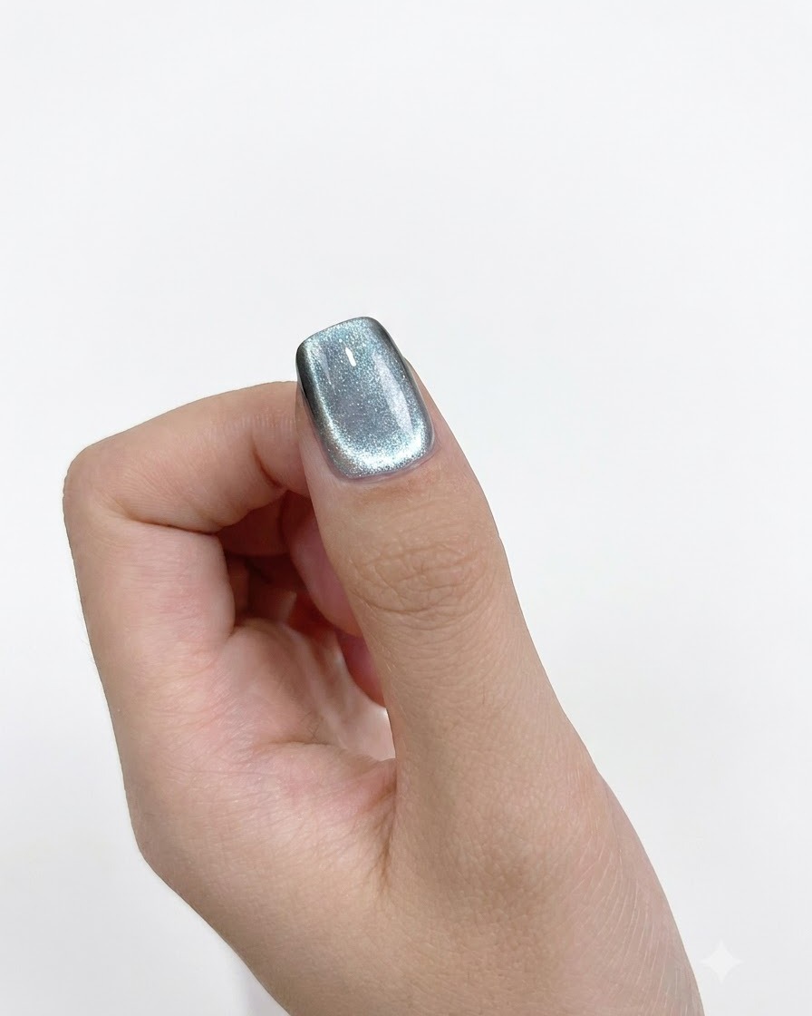 Nahaufnahme eines zylindrischen Magneten, der präzise an die linke Seite eines lackierten Nagels gehalten wird.