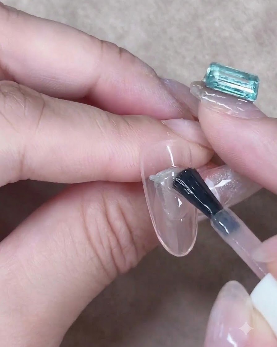Ein Gelpinsel glättet sorgfältig eine Schicht durchscheinendes Nude-Gel in der Mitte eines mandelförmigen Nagels.