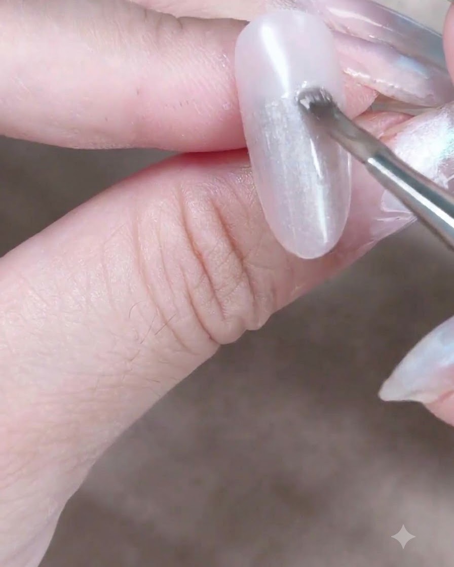 Ein zylindrischer Magnet wird nah an einen feuchten Cat-Eye-Gelnagel gehalten, um die magnetischen Schimmerpartikel zu bewegen.